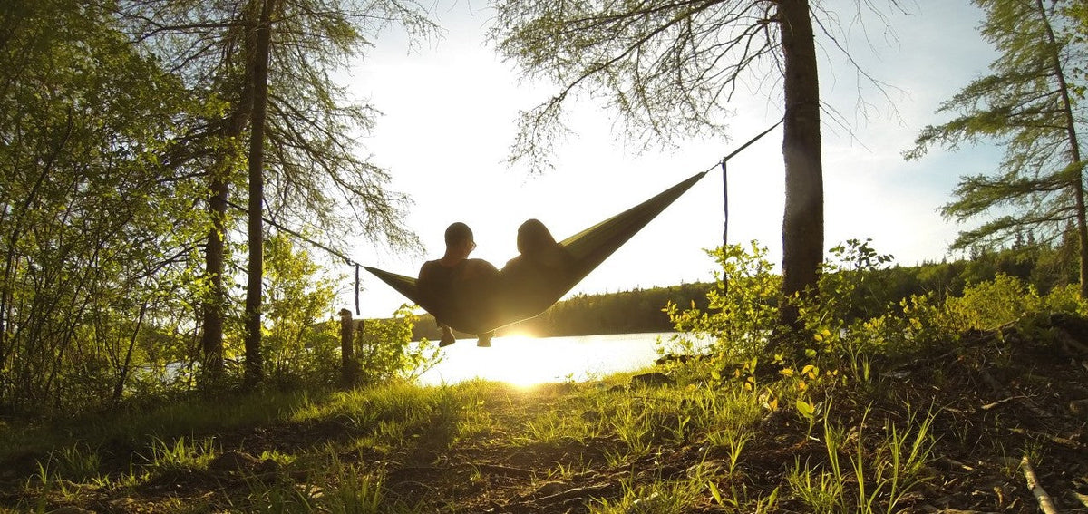 Two people hammocking in an ENO Hammock and looking at the sunset over a lake