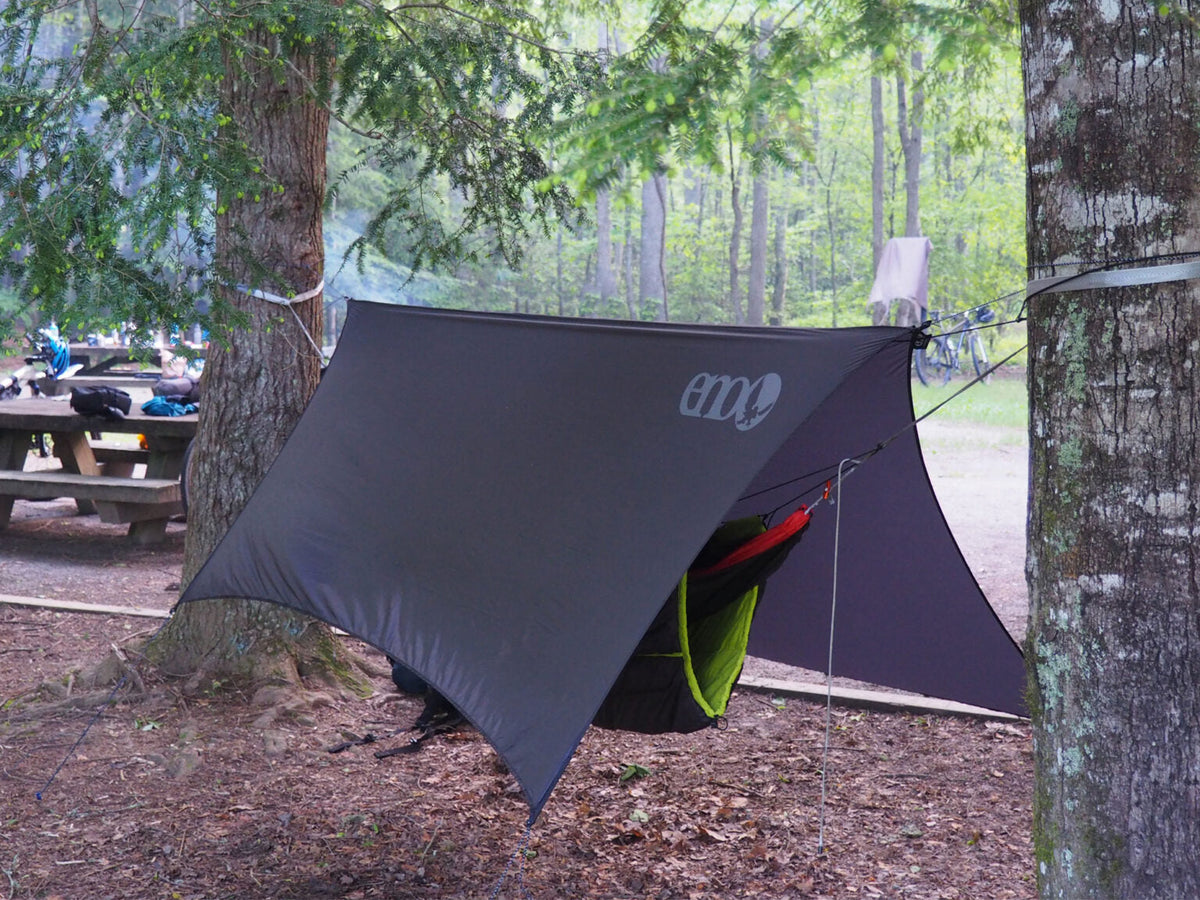 A charcoal ENO rain tarp over an ENO hammock set up in the trees