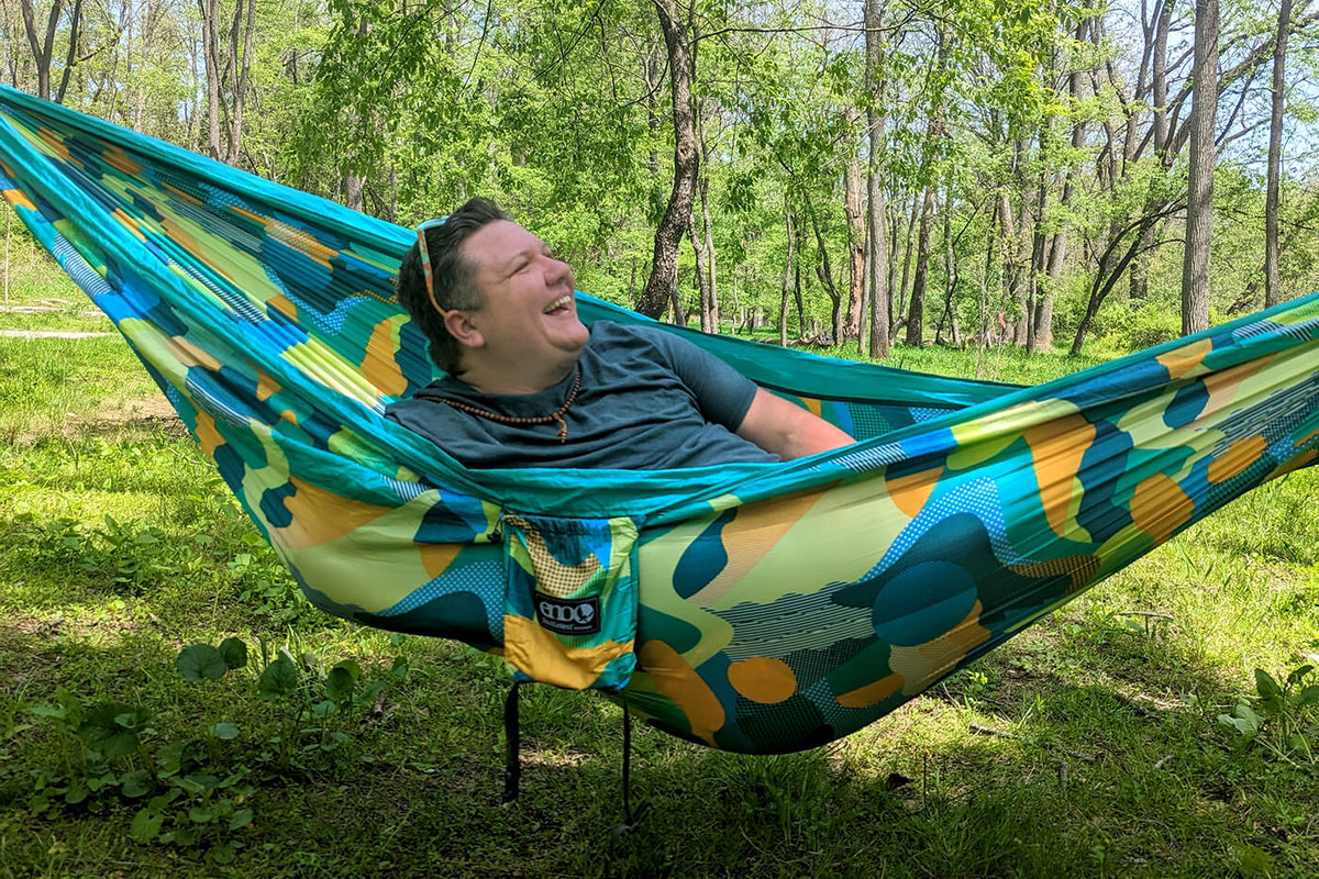 A trans man relaxes in an ENO DoubleNest Print Hammock.