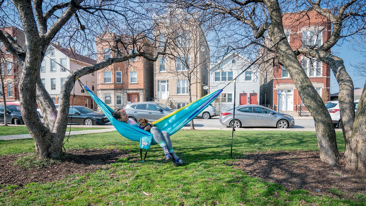 A woman lays in her ENO hammock while in an urban park
