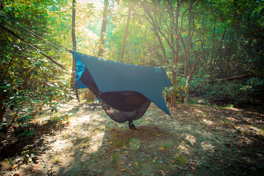An ENO hammock with an ENO rain tarp strung between trees