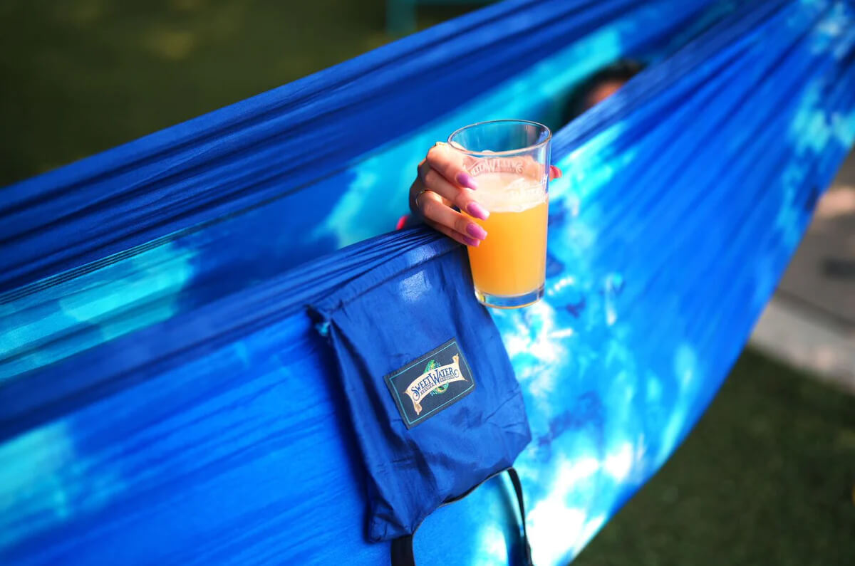 ENO x SweetWater hammock with a someone holding a drink