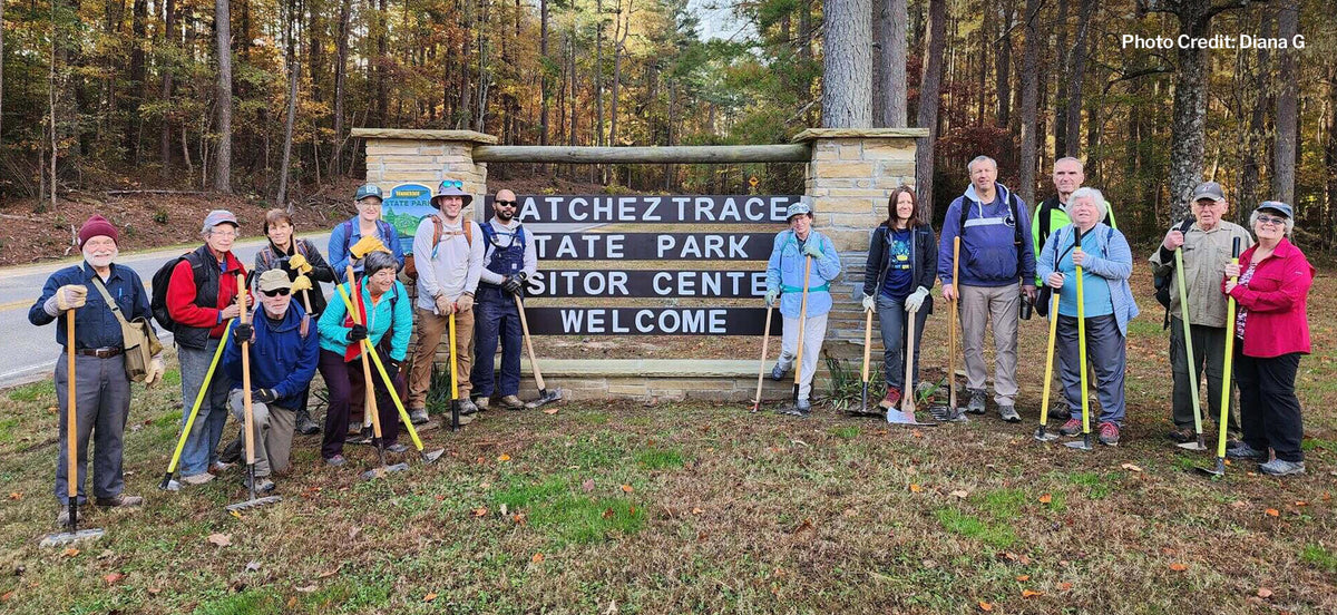 Group of people with shovels in front of Atchafalaya Trace State Park visitor center sign.