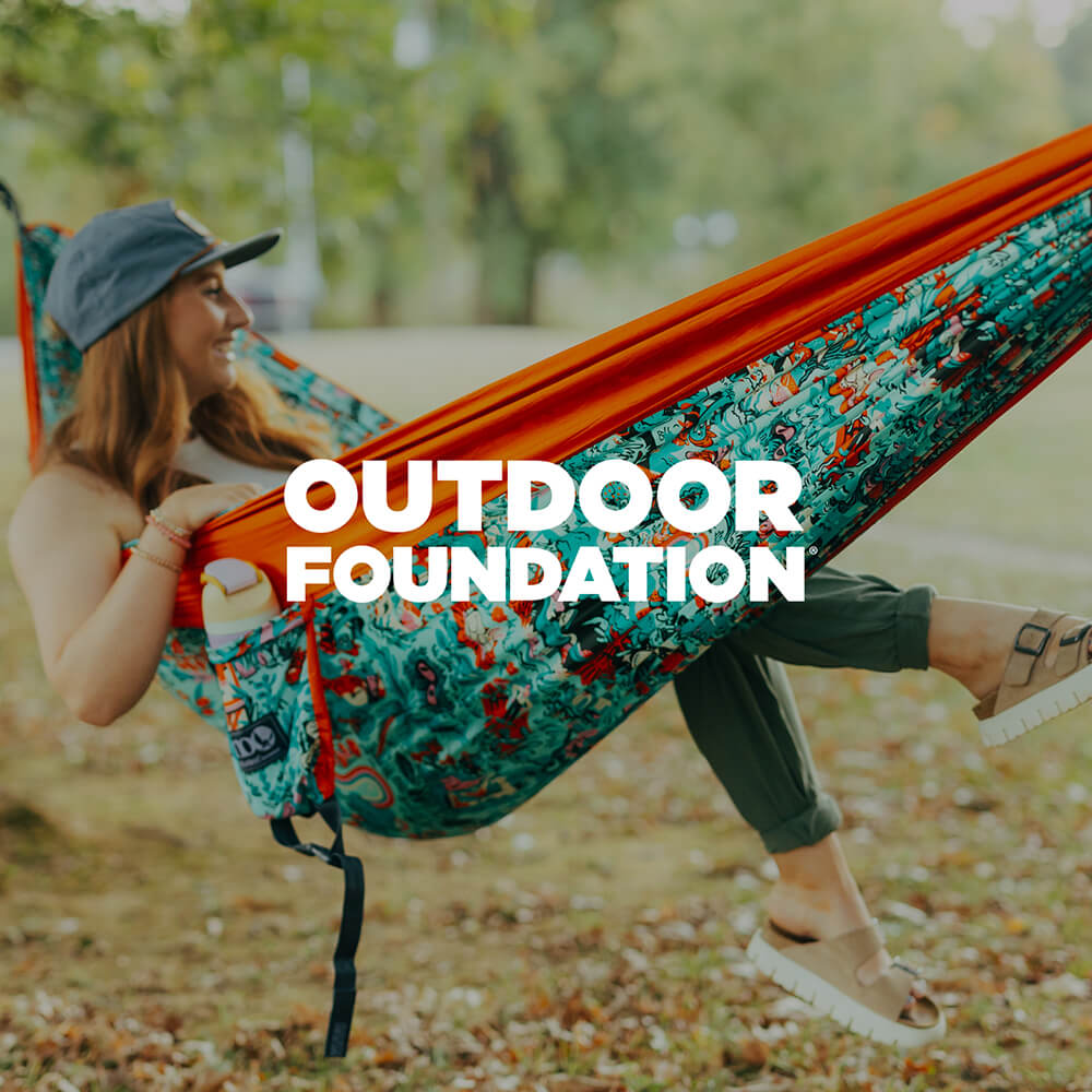 Person relaxing in an ENO Giving Back Hammock with the Outdoor Foundation logo overlaid.