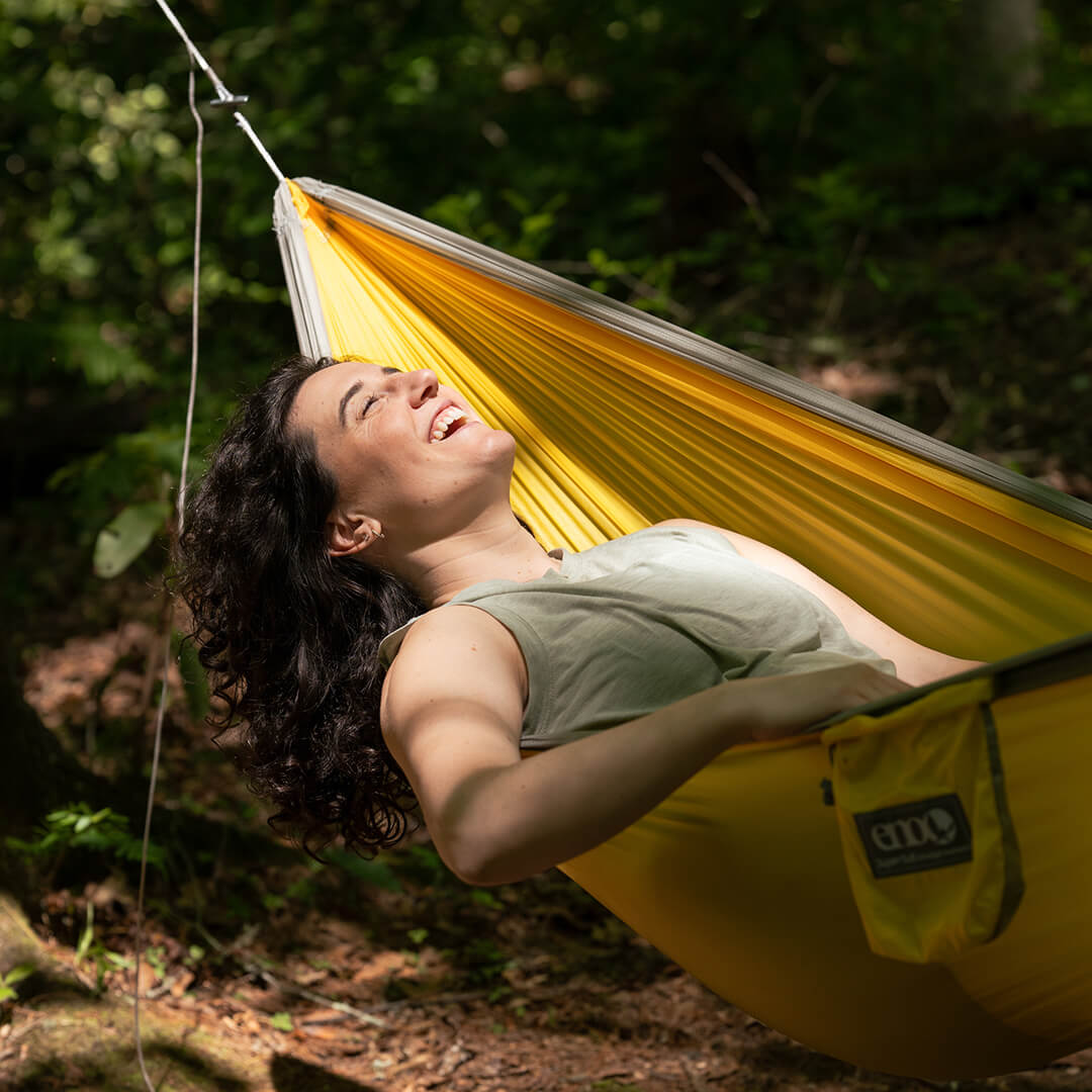 Person relaxing in a SuperSub Ultralight Hammock in a forest setting