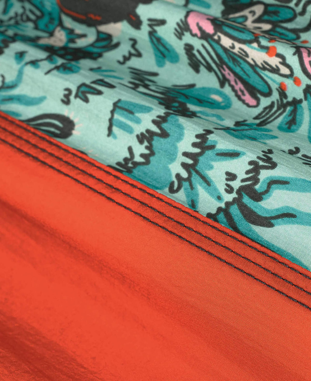 Close-up of a fabric with a colorful pattern and a red border.