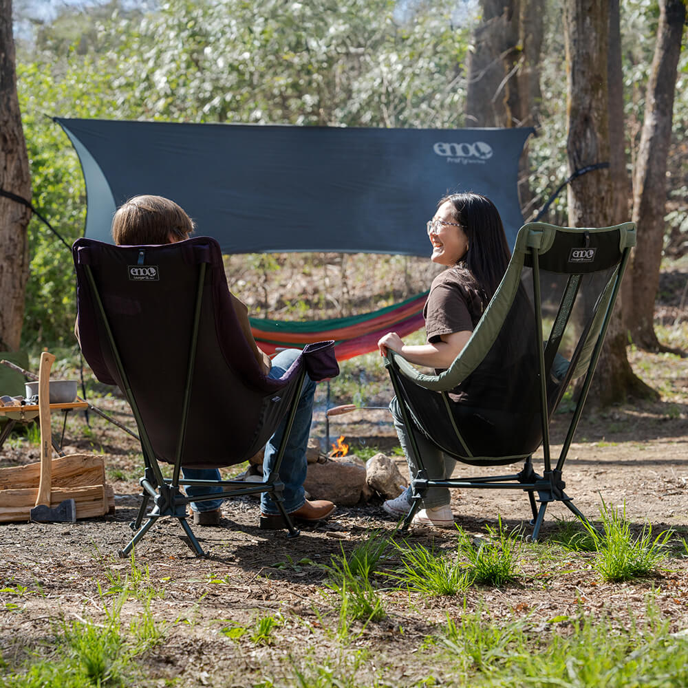Two friends sit fireside at their campsite in ENO Lounger DL Chairs, solid and mesh versions.