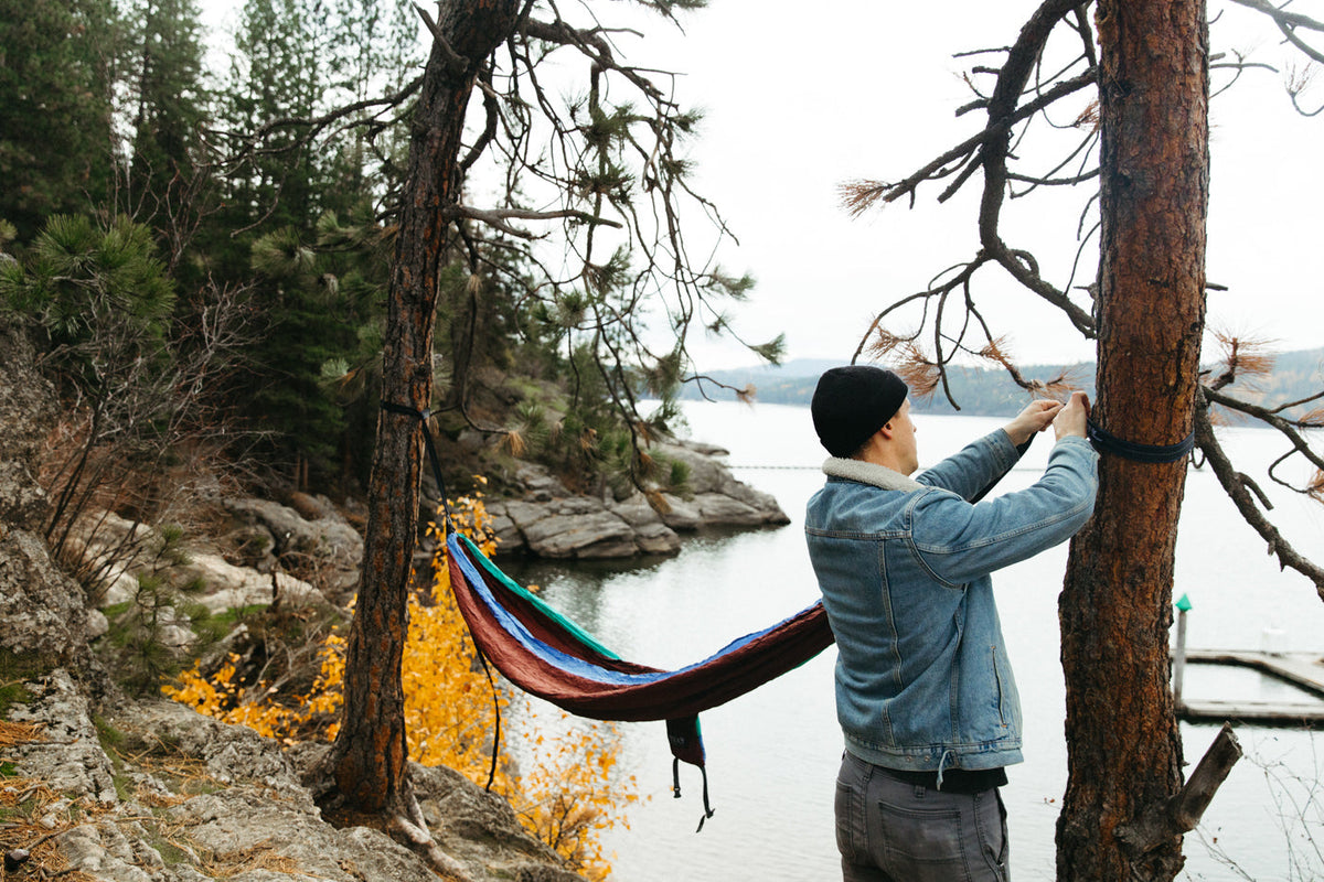 A man sets up his ENO hammock by a lake