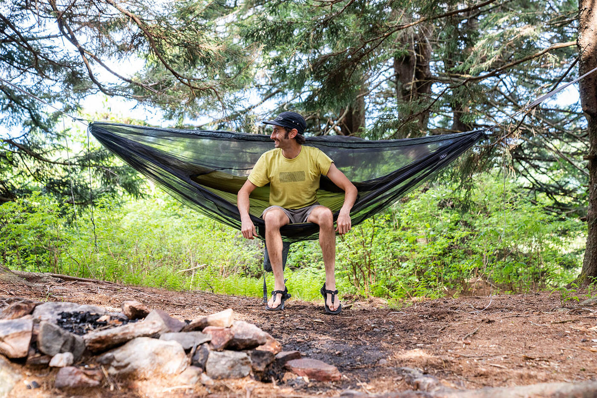 A man sitting in an ENO hammock in the woods