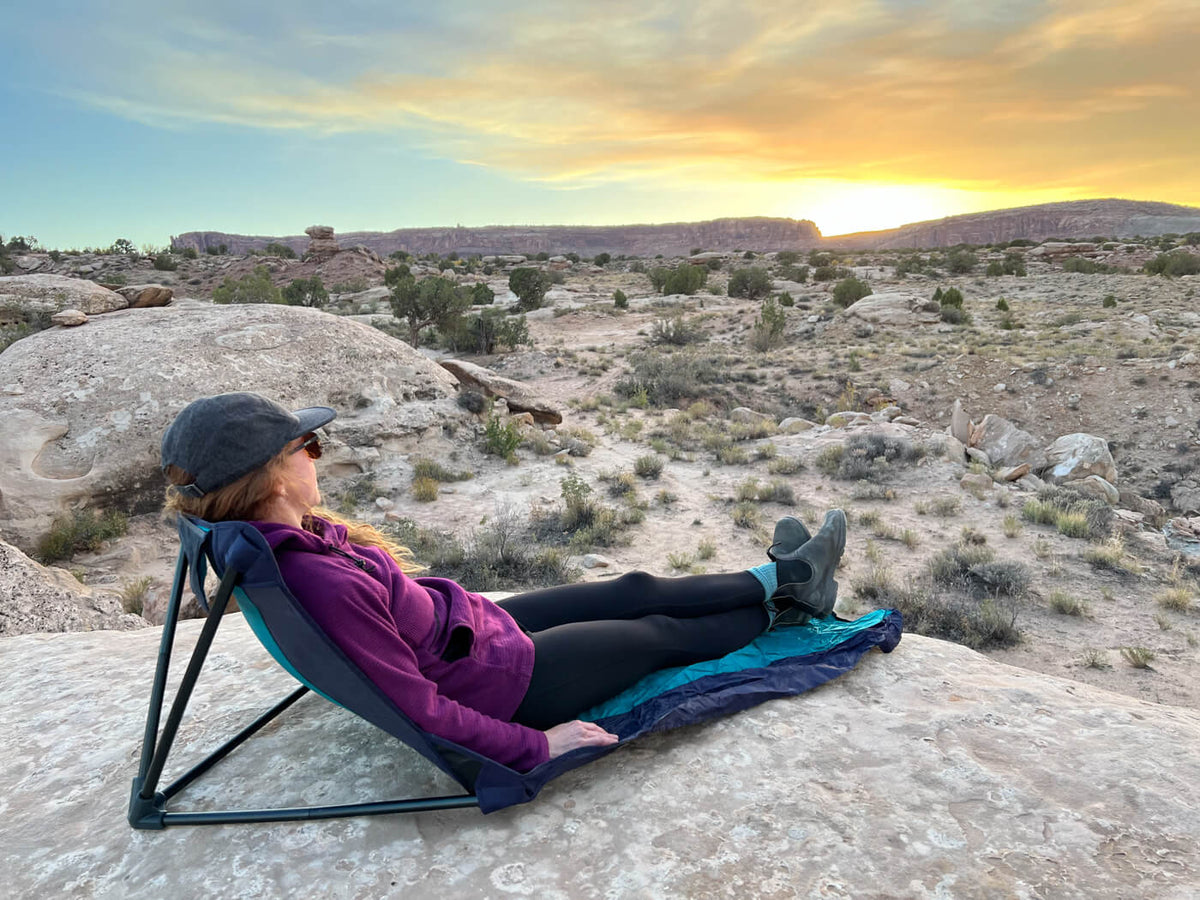A woman in an ENO Lounger GL Chair on a rock looking at the sunset