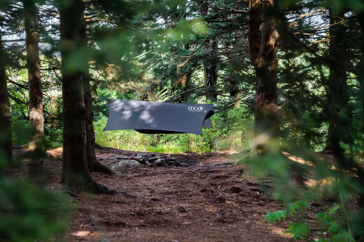 A charcoal colored ENO rain tarp over an ENO hammock in woods