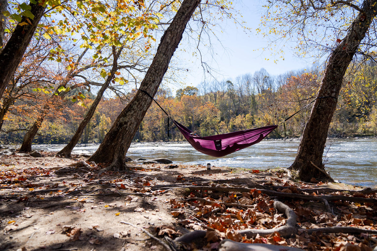 A person hammocking in an ENO Hammock by a lake