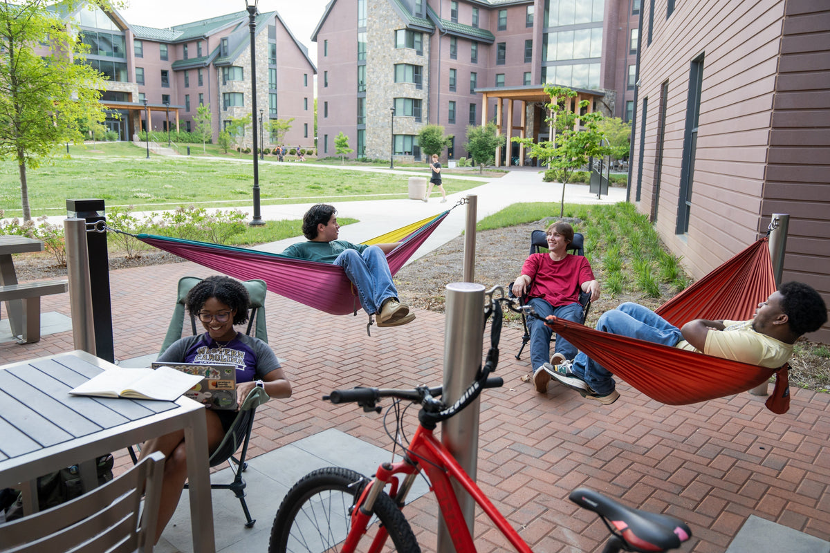 A group of friends hammocking in ENO hammocks and sitting in ENO Lounger Chairs in front of a dorm