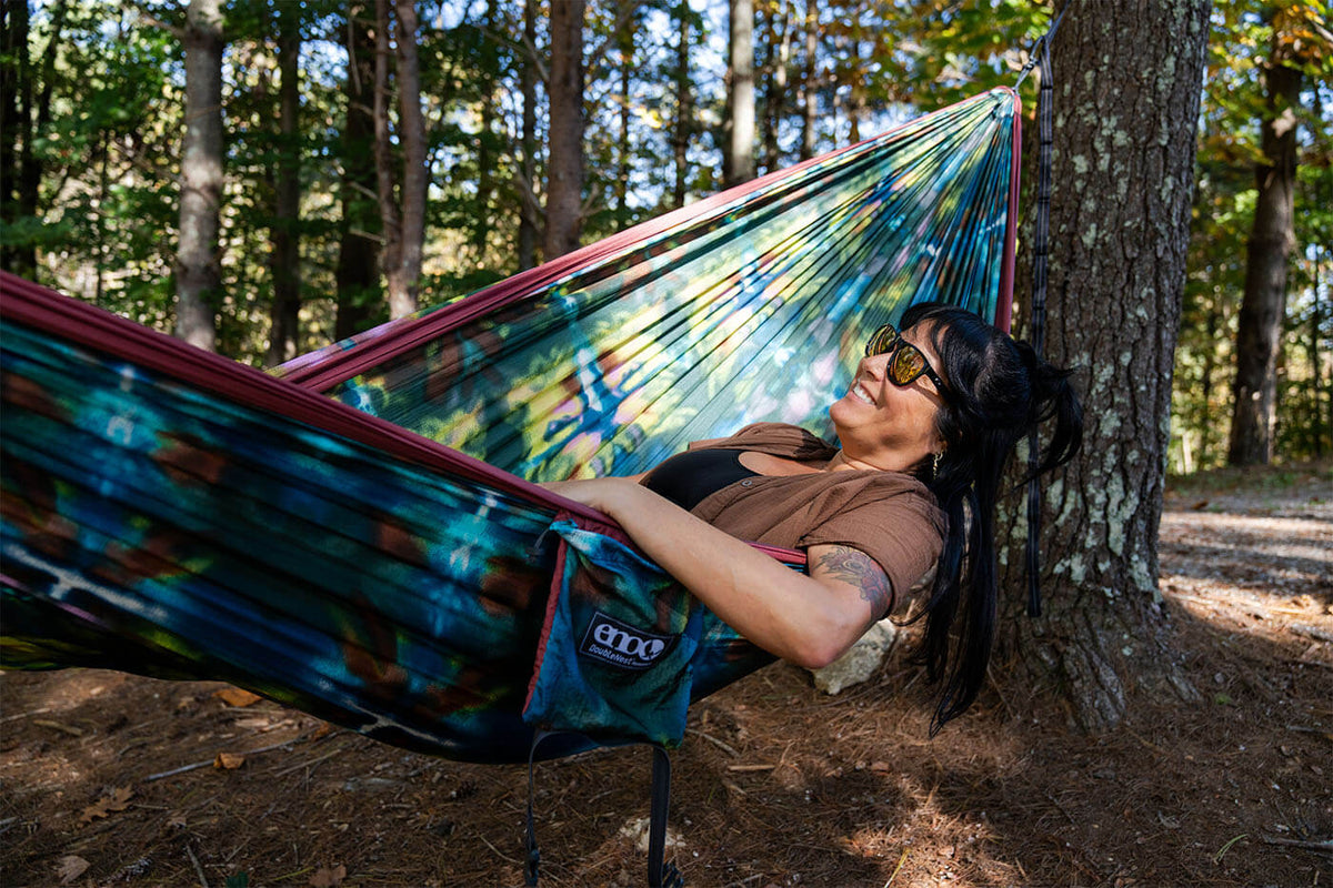 Natali Jackson laying in Shibori DoubleNest Hammock Print in the woods.