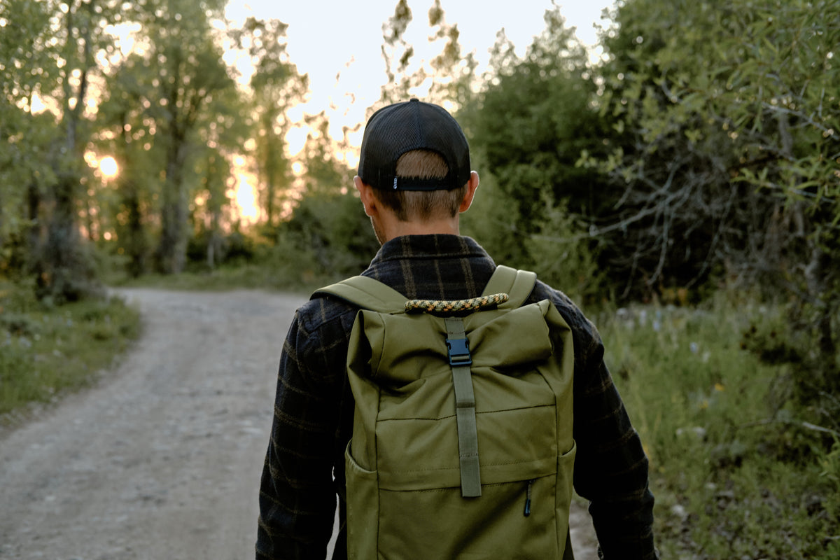 A man walking on a trail with a green ENO backpack on