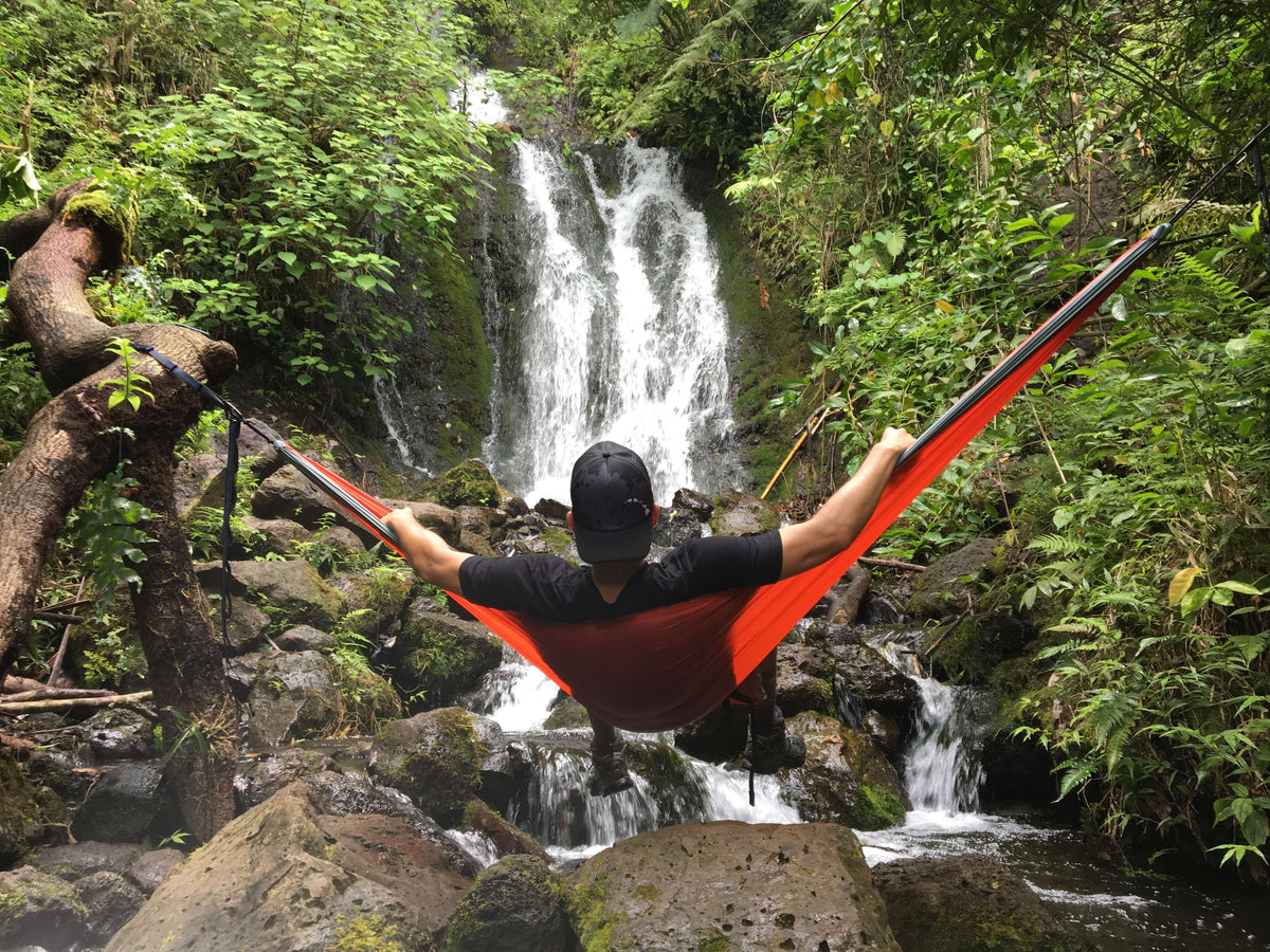 A man hammocking in an ENO Hammock and looking at a waterfall