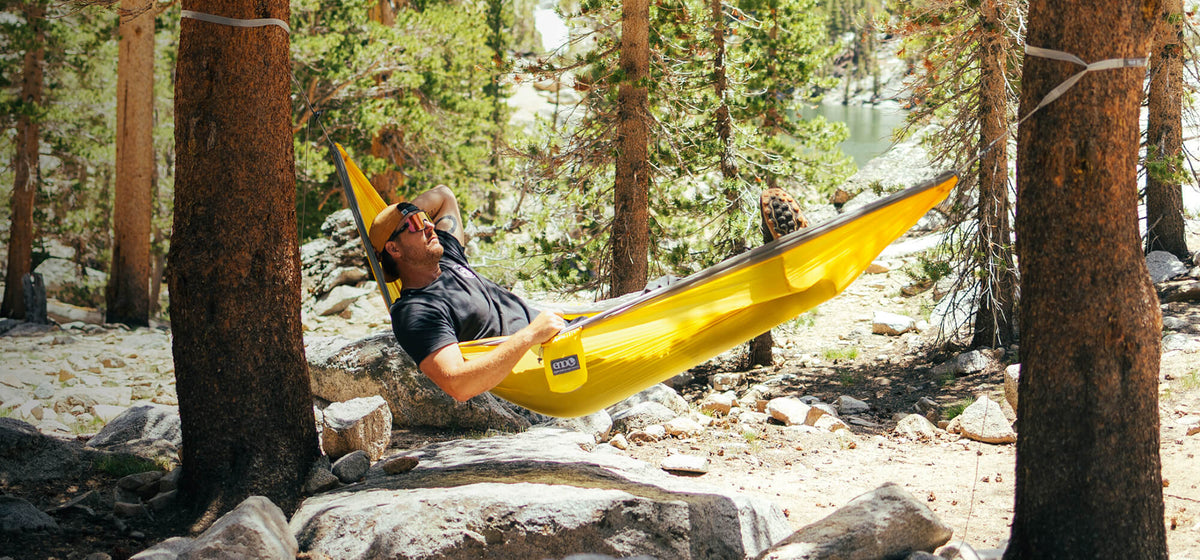 Ambassador Ryan T. laying back in a Yellow-Steel ENO SuperSub Ultralight Hammock in the forest.