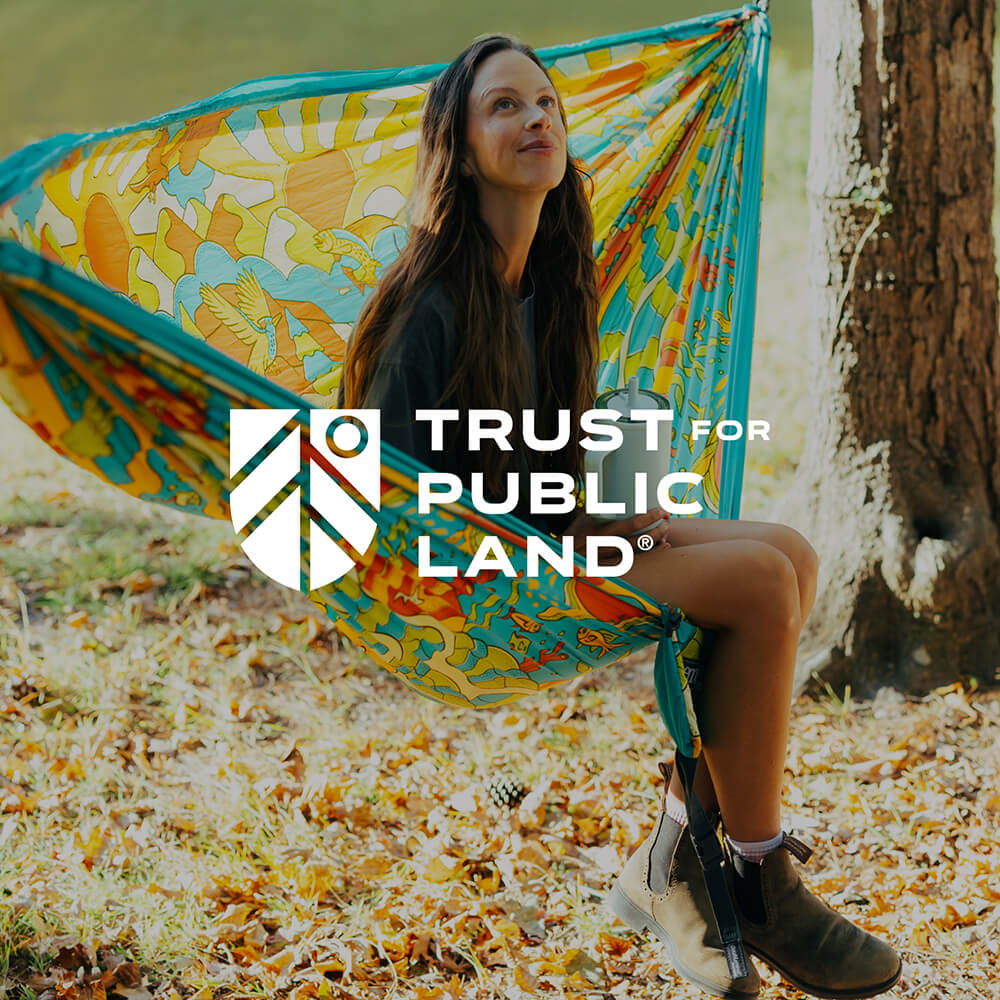 Woman sitting in an ENO Giving Back Hammock with the Trust for Public Land logo overlay
