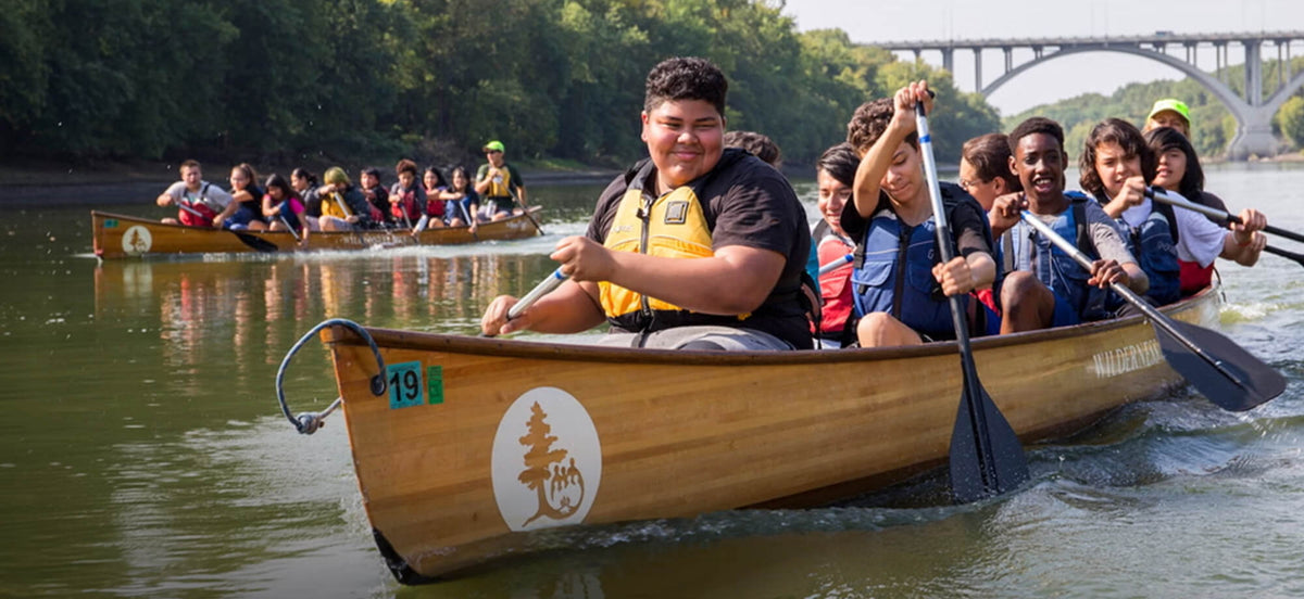 Group of people in canoes on a river with a bridge in the background